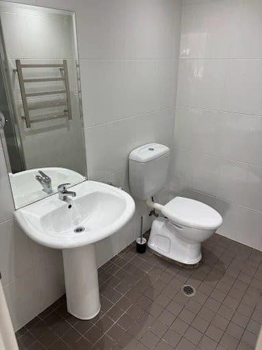Spotless bathroom with white pedestal sink and toilet after an end-of-lease clean