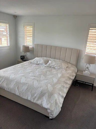 Freshly cleaned bedroom with made bed, shutters and vacuumed carpet