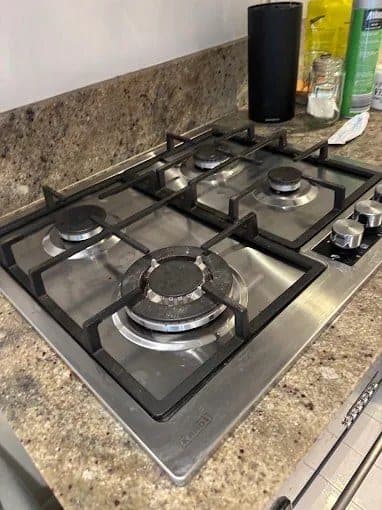 Spotless stainless-steel gas cooktop after a deep kitchen clean