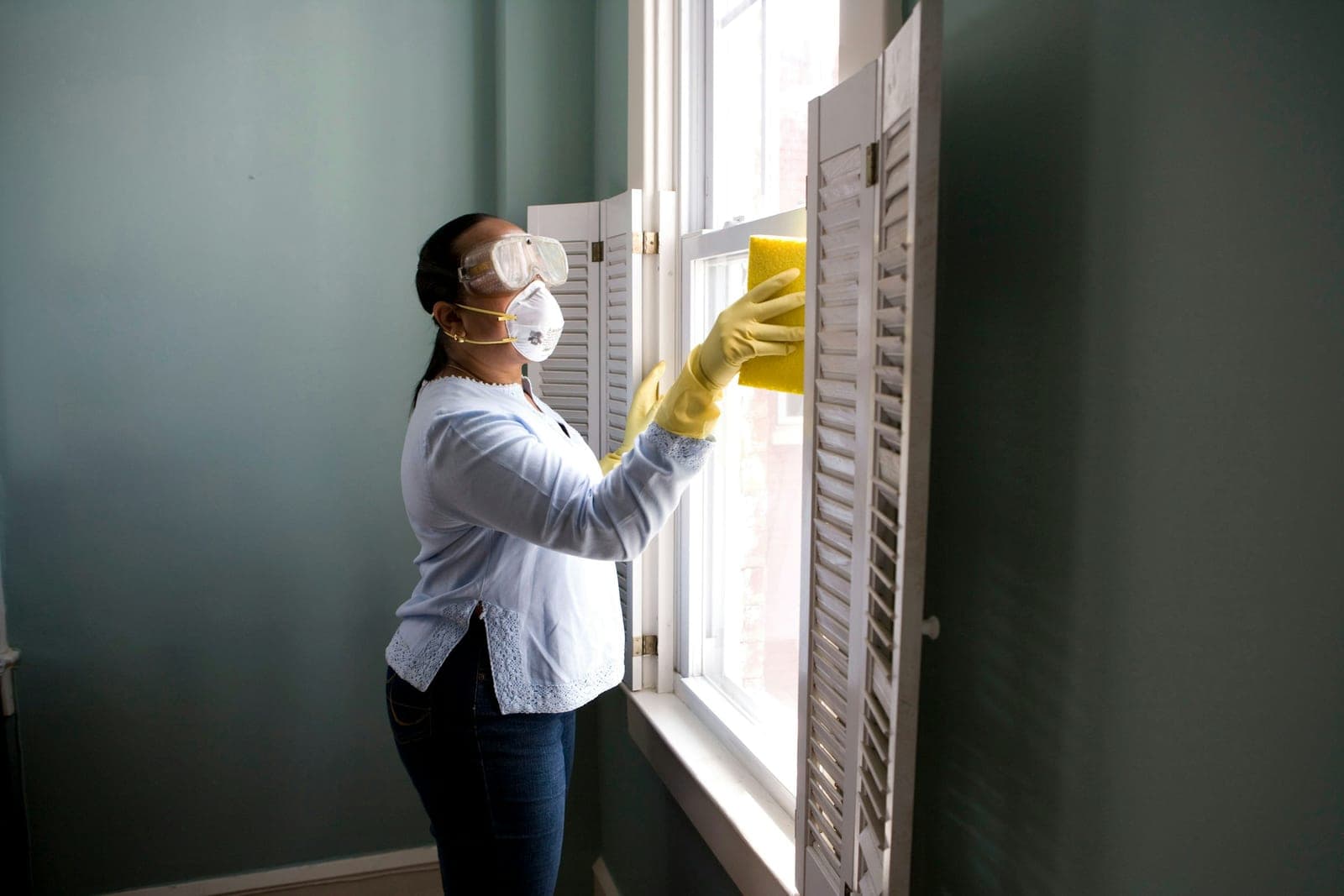 Person sponging a window pane in yellow gloves — illustrative of window cleaning for Sydney homes