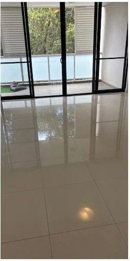 Polished tiled living-room floor reflecting balcony doors after cleaning