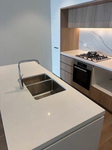 Kitchen island with double sink, gas cooktop and timber cabinets after cleaning